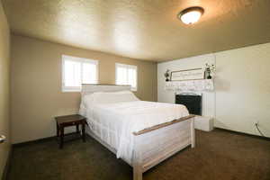 Bedroom featuring dark colored carpet, a textured ceiling, and baseboards