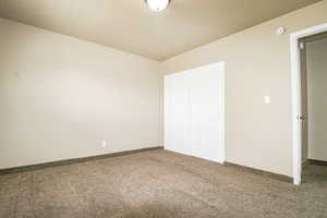 Unfurnished bedroom with baseboards, carpet, and a closet