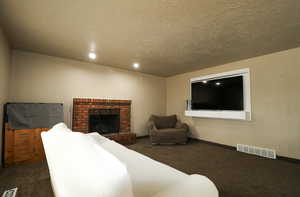 Carpeted living room with a textured ceiling, baseboards, and visible vents