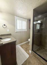 Bathroom featuring vanity, toilet, plenty of natural light, tile patterned floors, and a shower stall