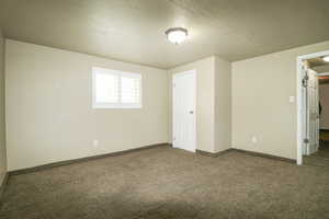 Unfurnished bedroom with carpet floors, a textured ceiling, and baseboards