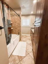 Bathroom featuring shower / bath combo with shower curtain, tile patterned flooring, baseboards, recessed lighting, and a textured ceiling