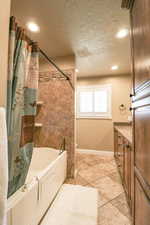 Full bathroom with baseboards, a textured ceiling, tile patterned floors, and shower / bath combination with curtain