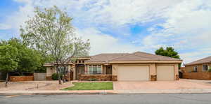 View of front of home with an attached garage, stucco siding, a tiled roof, and stone siding