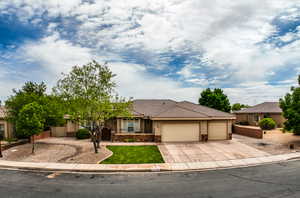 Ranch-style home featuring stone siding, stucco siding, a tiled roof, concrete driveway, and an attached garage
