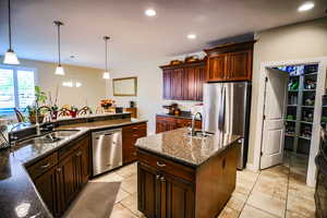 Kitchen featuring hanging light fixtures, appliances with stainless steel finishes, a sink, and dark stone countertops