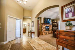 Foyer featuring arched walkways, baseboards, a stone fireplace, and light tile patterned floors