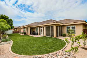 Back of property featuring fence, stucco siding, a sunroom, a patio, and a tiled roof