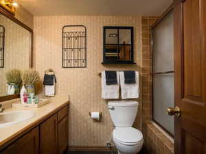 Full bathroom with toilet, vanity, and a textured ceiling