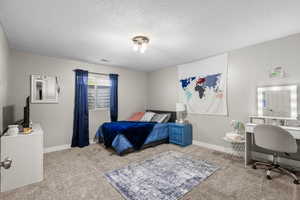 Bedroom with carpet floors, a textured ceiling, and baseboards