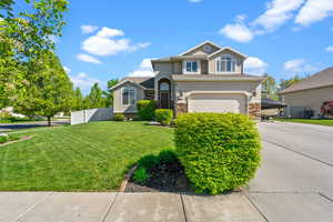 View of front facade with an attached garage, stucco siding, driveway, and stone siding