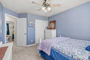 Bedroom with a ceiling fan, baseboards, light colored carpet, and a closet