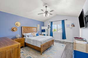 Bedroom with baseboards, lofted ceiling, wood finished floors, and ceiling fan
