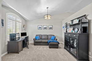 Office area with light colored carpet, baseboards, and vaulted ceiling