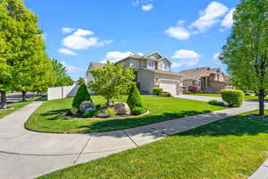 View of front facade with driveway, a garage, fence, a front lawn, and stucco siding