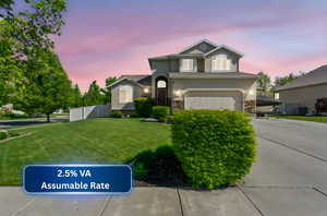 Traditional-style house with an attached garage, a front lawn, stone siding, stucco siding, and concrete driveway