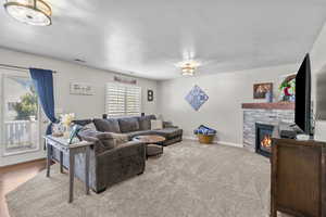 Living area with visible vents, a textured ceiling, a brick fireplace, and baseboards