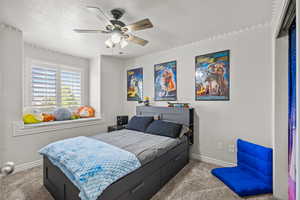 Bedroom with baseboards, a textured ceiling, carpet, and ceiling fan
