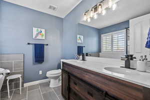 Bathroom featuring a sink, double vanity, toilet, tile patterned floors, and visible vents
