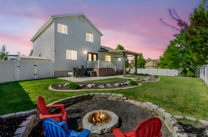 Back of property at dusk featuring an outdoor fire pit, a fenced backyard, a gate, a patio area, and a yard