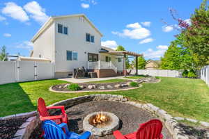 Back of house featuring a lawn, a gate, a fenced backyard, a patio, and a fire pit