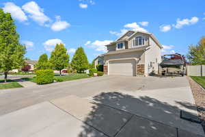 View of front of home featuring fence, a garage, driveway, and stone siding