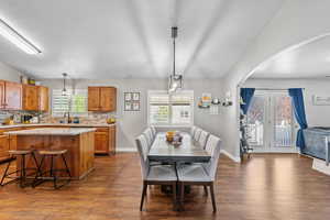 Dining room featuring baseboards, arched walkways, and dark wood-style floors