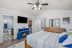 Bedroom with a closet, wood finished floors, a walk in closet, ensuite bath, and vaulted ceiling