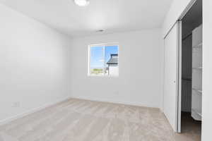 Unfurnished bedroom with light colored carpet, a closet, visible vents, and baseboards