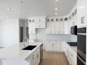 Kitchen featuring appliances with stainless steel finishes, a sink, light countertops, recessed lighting, and light wood-type flooring