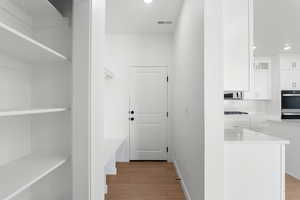 Hall featuring visible vents, light wood-style flooring, baseboards, and recessed lighting