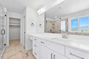 Full bath featuring a stall shower, marble finish floor, visible vents, vanity, and a walk in closet