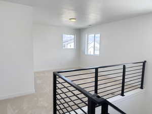 Stairway featuring carpet floors, a textured ceiling, and baseboards