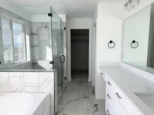 Bathroom with vanity, marble finish floor, a spacious closet, a garden tub, and a stall shower