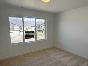 Spare room featuring carpet flooring, baseboards, visible vents, and a residential view
