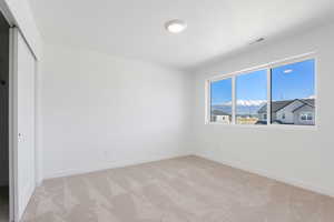 Unfurnished bedroom with light colored carpet, a closet, visible vents, and baseboards