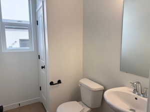 Bathroom featuring toilet, baseboards, and a sink