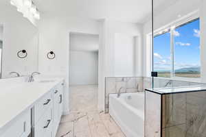 Bathroom featuring baseboards, marble finish floor, a garden tub, and vanity