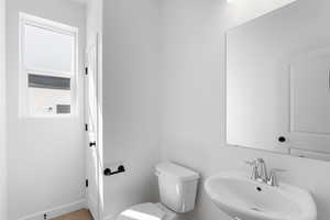 Half bathroom with toilet, baseboards, and a sink