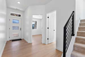Entrance foyer with baseboards, stairs, visible vents, and light wood-type flooring