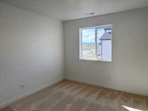 Unfurnished room featuring baseboards, visible vents, and light colored carpet