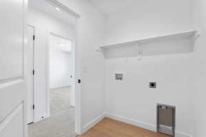 Clothes washing area featuring laundry area, hookup for an electric dryer, light wood finished floors, baseboards, and hookup for a washing machine