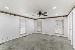 Spare room with ceiling fan, visible vents, plenty of natural light, and carpet