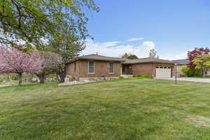 Ranch-style home with brick siding, a garage, a front lawn, and concrete driveway