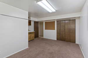 Interior space with a textured ceiling, light carpet, and baseboards