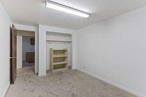 Unfurnished bedroom with a textured ceiling, baseboards, carpet, and a closet