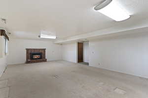 Finished below grade area with carpet floors, a textured ceiling, and a fireplace