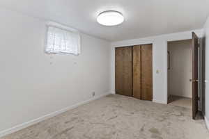 Unfurnished bedroom with carpet floors, a textured ceiling, baseboards, and a closet