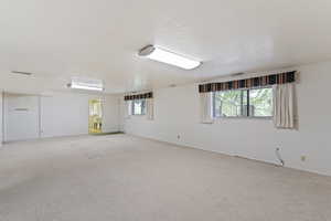 Spare room with light colored carpet, baseboards, a wealth of natural light, and visible vents