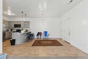 Kitchen featuring gray cabinetry, stainless steel appliances, light wood-style floors, and a kitchen breakfast bar